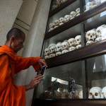 A Buddhist monk stands next to a glass case containing 5,000 human skulls belonging to Khmer Rouge victims as people gather to mark the 41st anniversary of the start of the regime