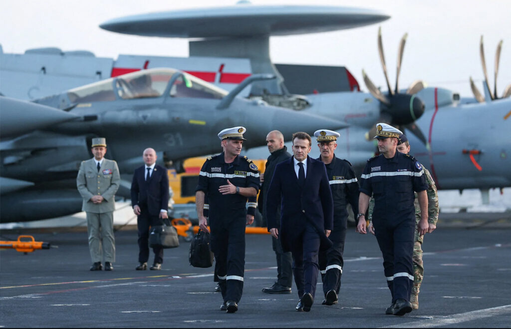 ប្រធានាធិបតី​បារាំង លោក Emmanuel Macron (រូប​កណ្ដាល) ក្នុង​ដំណើរ​ទៅ​ត្រួតពិនិត្យ និង​សួរសុខទុក្ខ​កងទ័ព​បារាំង នៅ​លើ​នាវា​ផ្ទុក​យន្តហោះ Charles de Gaulle កាលពី​ថ្ងៃ​ចន្ទ ទី​៩ ខែ​មីនា ឆ្នាំ​២០២៦។